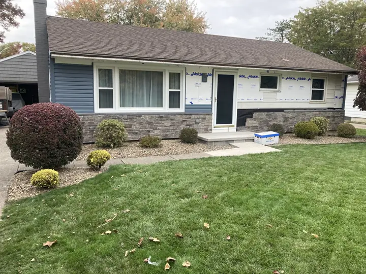 Blue siding and stone installation in progress